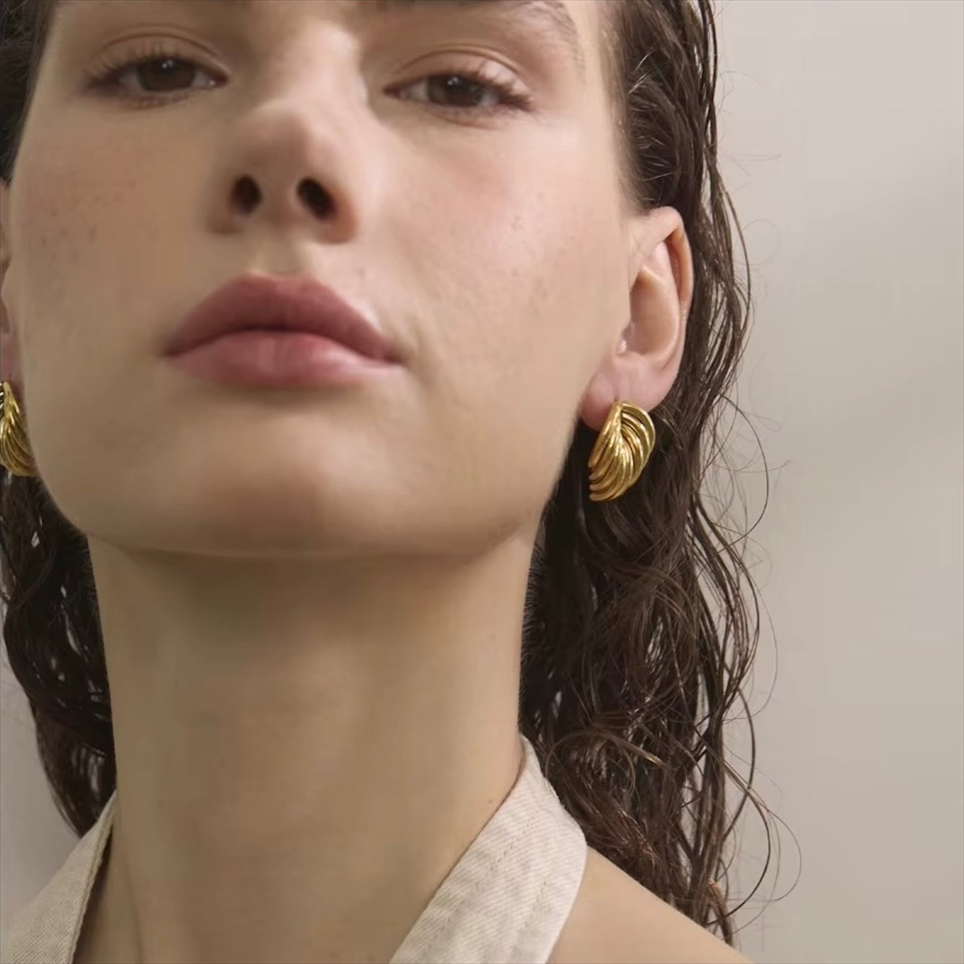 Boucles d'oreilles dorées en acier inoxydable au design ondulé pour femme, élégance et modernité.