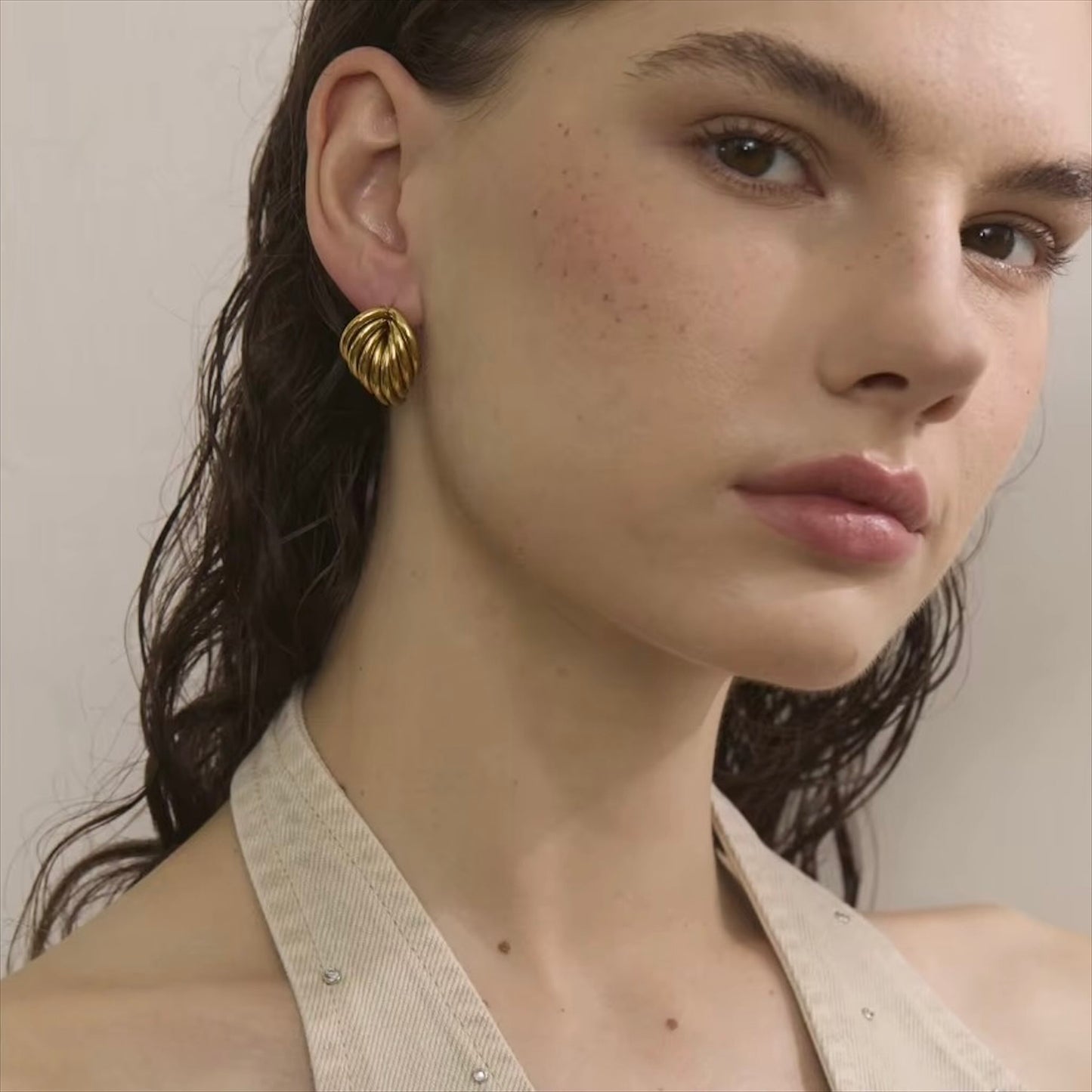 Boucles d'oreilles dorées en acier inoxydable au design ondulé pour femme, élégance et modernité.