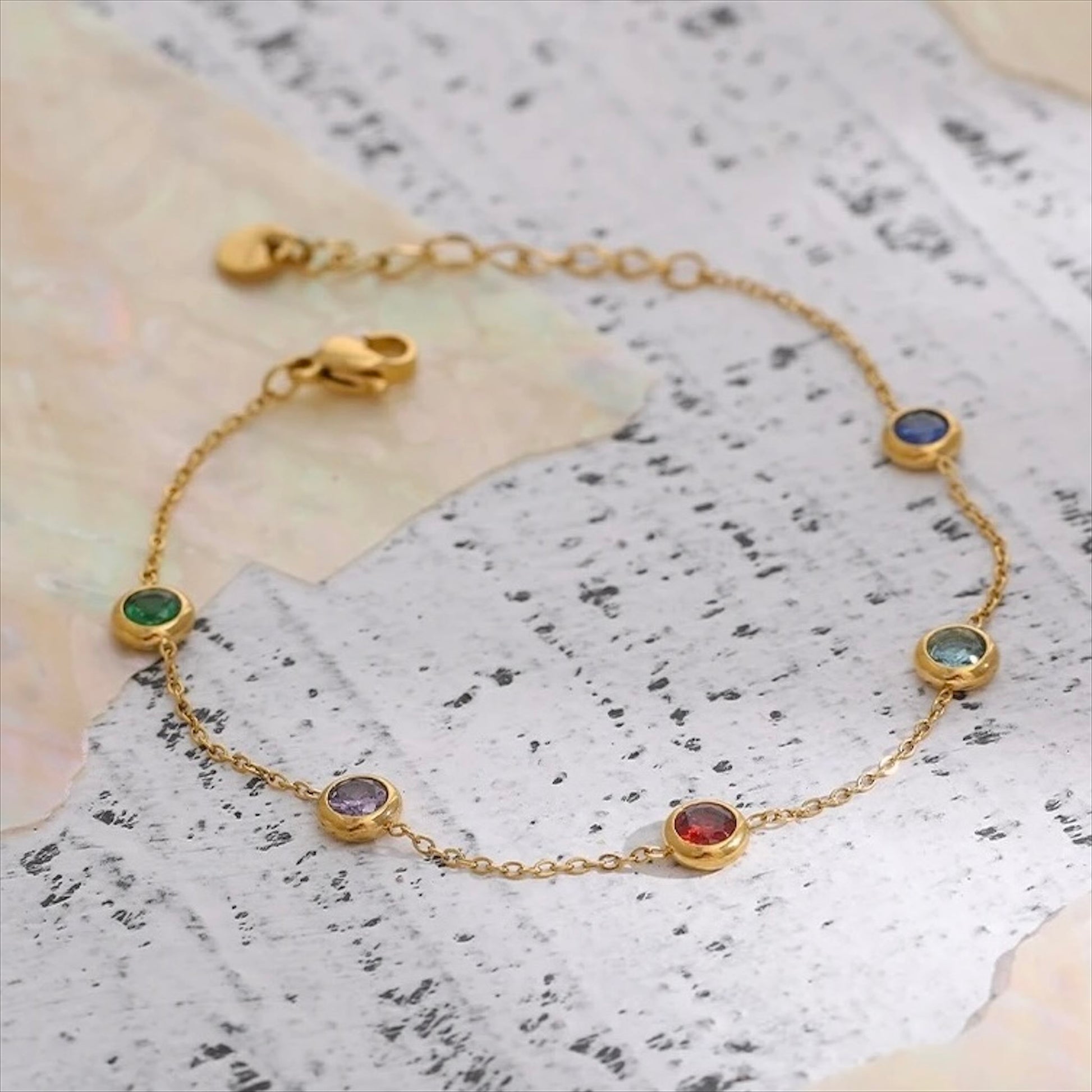 Bracelet fin doré en acier inoxydable avec pampilles pierres colorées, bijou délicat et tendance pour femme.